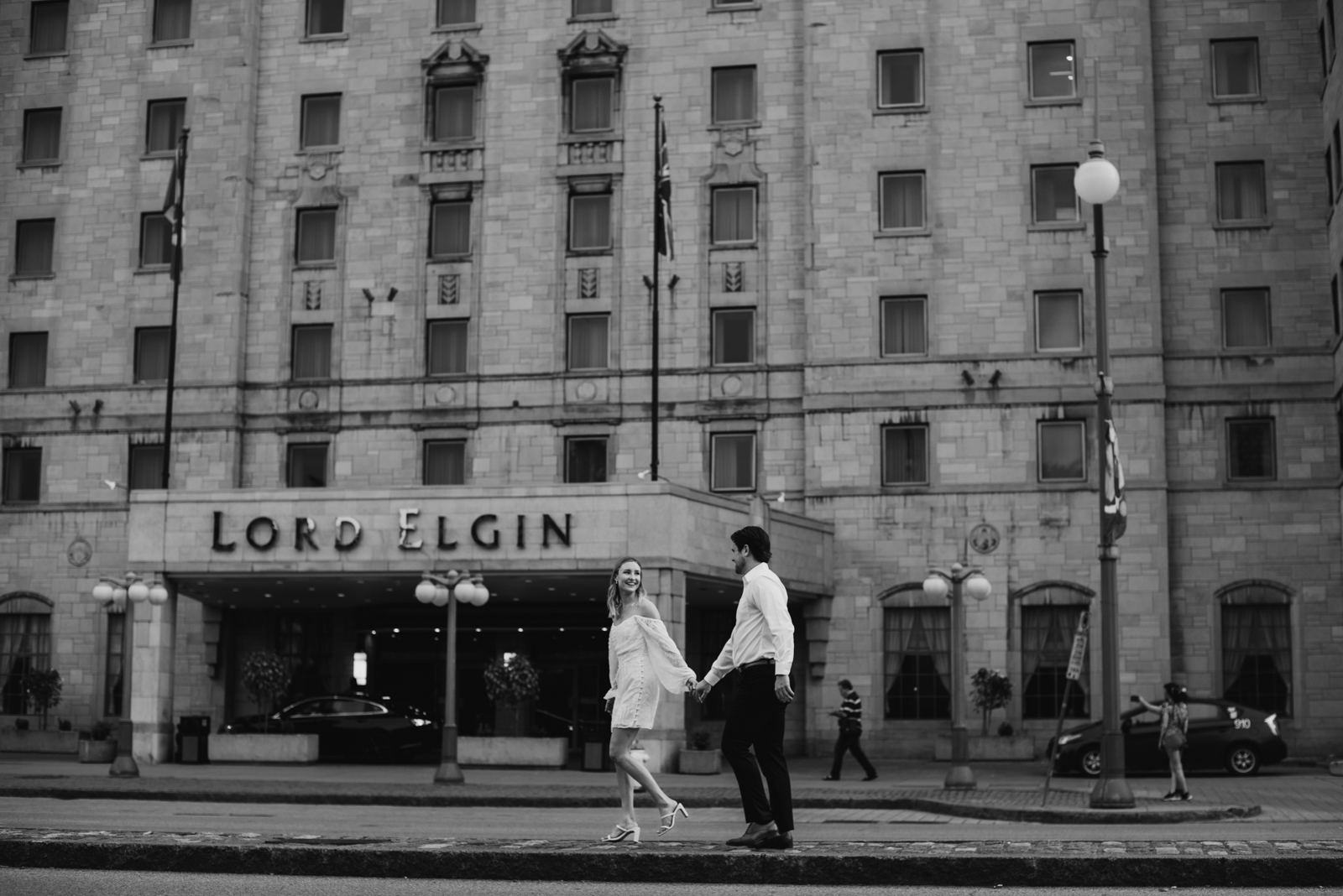 Engaged couple walking in front of in front of the Lord Elgin Hotel