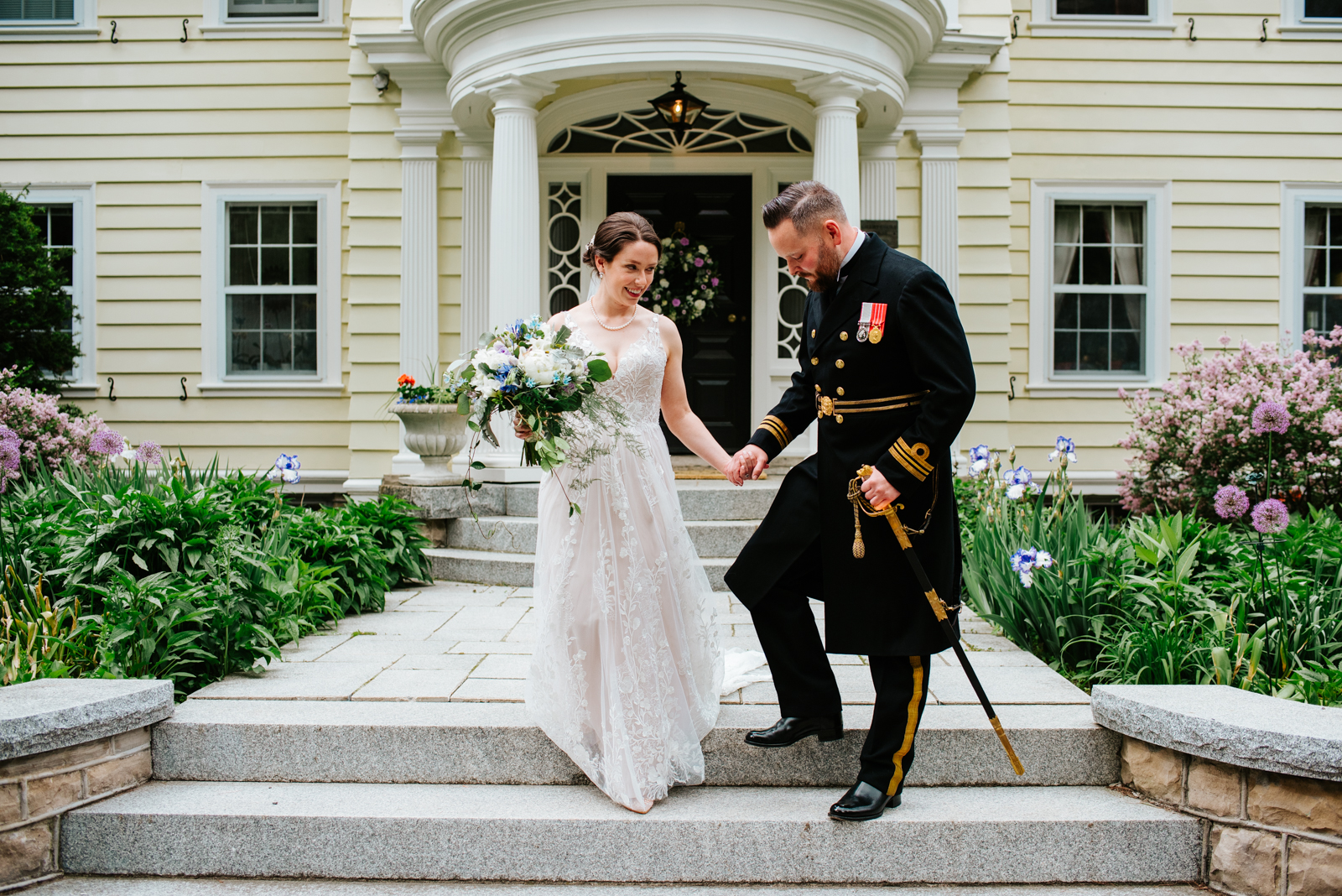 bride and groom in canadian navy uniform with sword walking down stairs of private estate