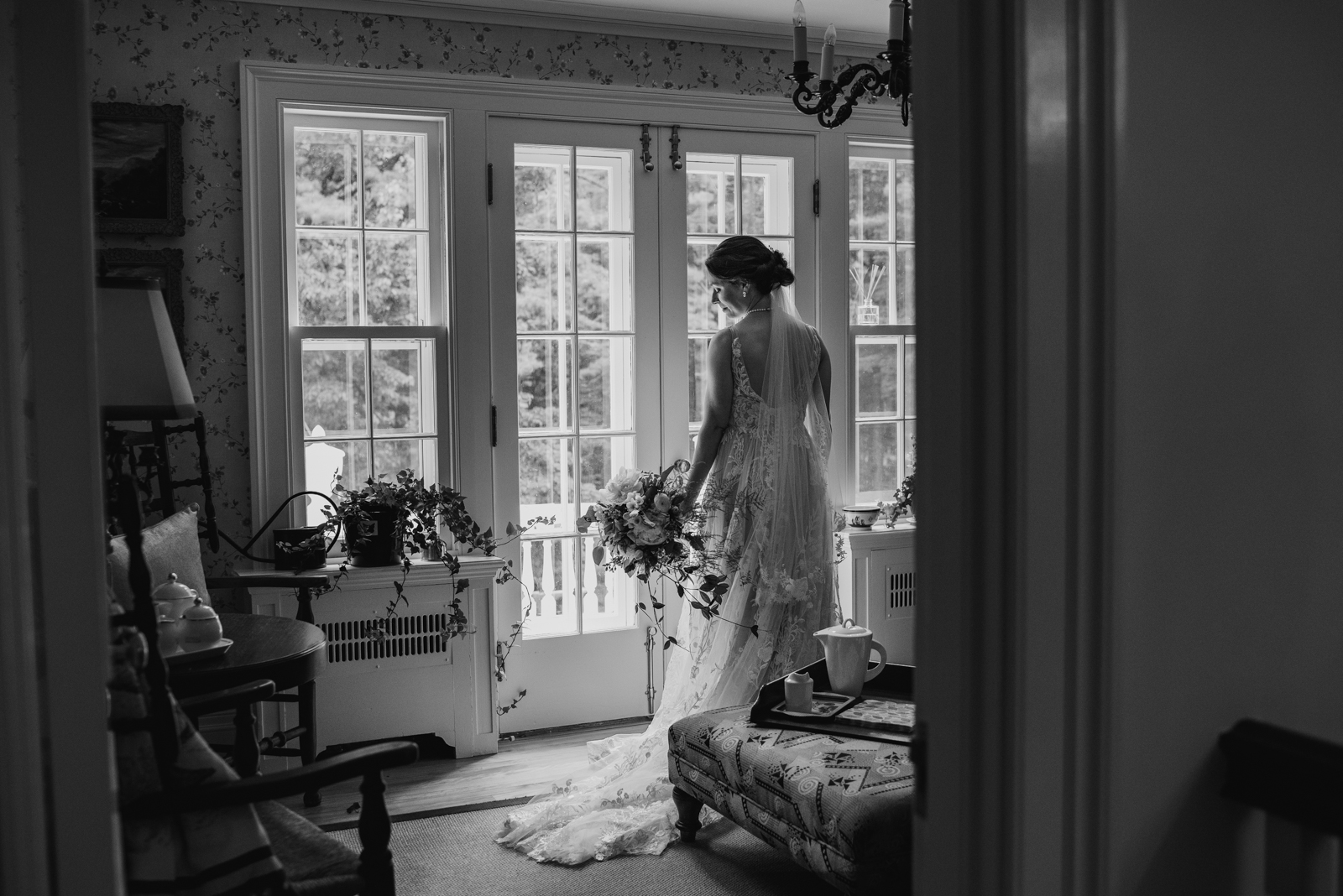bride waiting for the ceremony to start by the window holding wedding bouquet in black and white