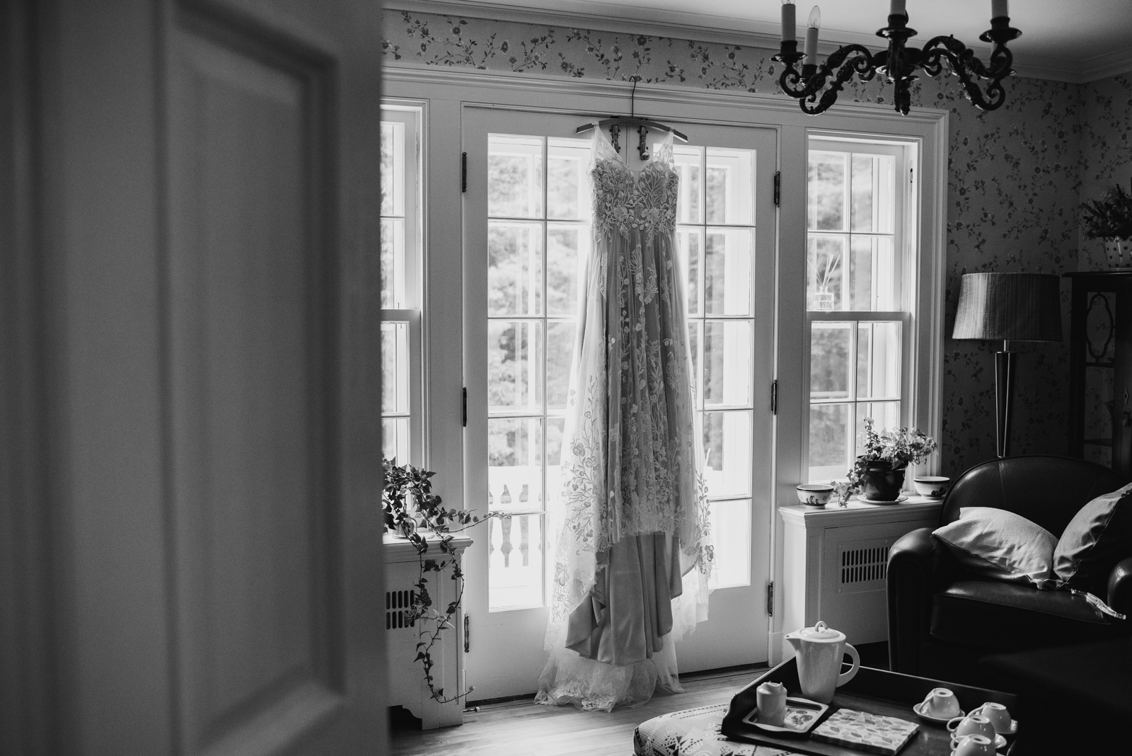 wedding dress hanging from window sill in black and white