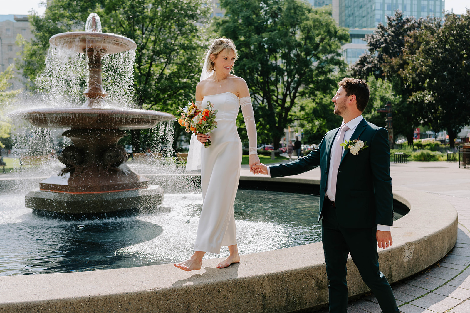 bride and groom walking on fountain at confederation park in ottawa